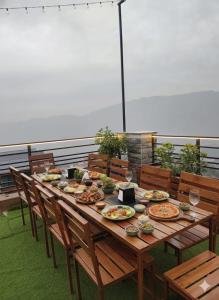 a wooden table with plates of food on a balcony at Silver wings Kasauli in Kasauli