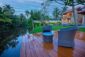a wooden deck with two chairs and a house at La Lassaura in Unawatuna