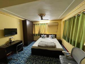 a bedroom with a bed and a desk and a television at PlatinumIN Guesthouse in kolkata