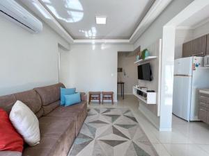 ein Wohnzimmer mit Sofa und eine Küche in der Unterkunft Apartmento próximo ao mar in Capão da Canoa