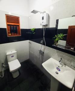a bathroom with a white toilet and a sink at Meadow view unawatuna in Galle