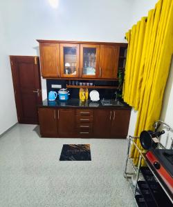 a kitchen with wooden cabinets and yellow curtains at Meadow view unawatuna in Galle