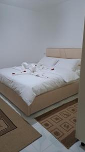 a bed with white sheets and red roses on it at Aleko Guesthouse in Përmet