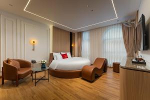 a hotel room with a bed and two chairs at Lam Anh Hotel 9 Him Lam Vạn Phúc in Hà Ðông