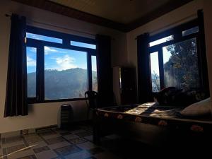 a bedroom with two windows and a bed with a view at A Home Above the Clouds Riturain Mukteshwar in Mukteshwar