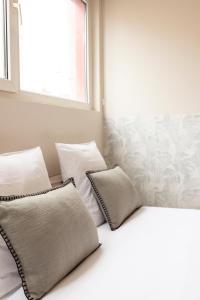 een slaapkamer met witte kussens en een raam bij Nice air-conditioned studio, close to Paris in Pré Saint Gervais