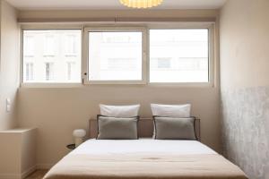 een slaapkamer met een bed en twee ramen bij Nice air-conditioned studio, close to Paris in Pré Saint Gervais +3 foto's