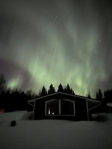 a house with a window in the snow under the aurora at Saagala Village in Tornio