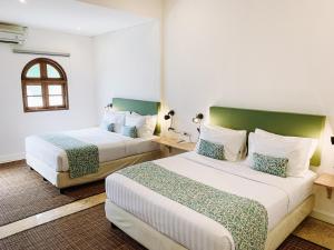 a hotel room with two beds and a window at Kresna By The Sea By Kresna Hospitality in Seminyak