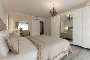 une chambre avec un grand lit blanc et un lustre dans l'établissement Villa Viktoria with private pool, barbecue, gym, children's playground, à Krivodol 52 autres photos