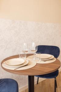 a wooden table with plates and wine glasses on it at Charming and air-conditioned - Close to Paris in Le Pré-Saint-Gervais +3 photos