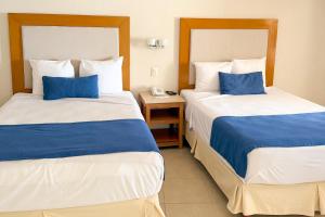 two beds in a hotel room with blue pillows at LXHotel Condomar in Puerto Vallarta