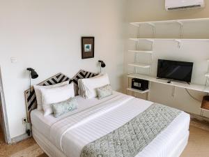 a bedroom with a large bed and a television at Kresna By The Sea By Kresna Hospitality in Seminyak