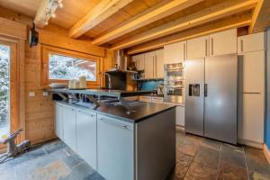 a kitchen with stainless steel appliances and wooden ceilings at Alpine Luxury Chalet Pool & Jacuzzi in Cordon