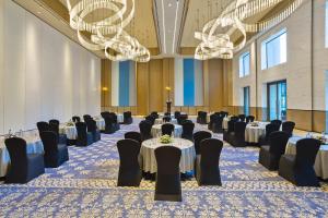 una sala banchetti con tavoli, sedie e lampadari a braccio di Fortune Select Siliguri a Binnāguri