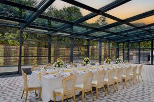 un lungo tavolo bianco con sedie in una stanza con finestre di Fortune Select Siliguri a Binnāguri Altre 8 foto