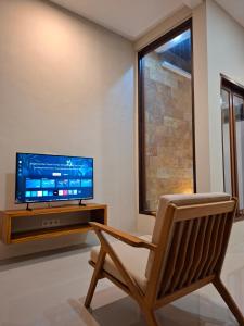 a living room with a chair and a television at Omi Homestay in Praya