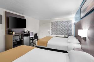 ein Hotelzimmer mit zwei Betten und einem Schreibtisch in der Unterkunft Rodeway Inn Lake Wales - Winter Haven in Lake Wales + 32 Fotos
