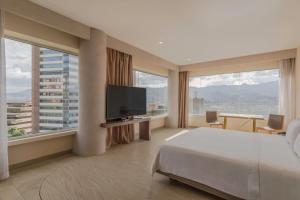 a hotel room with a bed and a flat screen tv at V Grand Hotel, a member of Radisson Individuals in Medellín