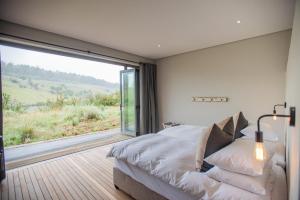 a bedroom with a bed and a large window at Star Dam Lodges in Dargle