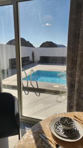 a view of a pool from a table with a glass window at sun in Būbādī