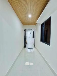 een gang met een houten plafond en een witte tegelvloer bij Homestay Kim Mỹ in Ấp Rạch Mẹo