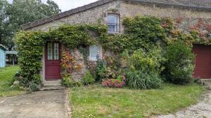 a brick house with a red door and flowers at Independent studio in nature in Saint-Valérien