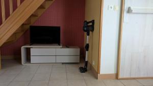 a room with a tv and a desk with a vacuum at Independent studio in nature in Saint-Valérien