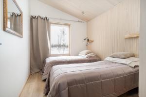 due letti in una stanza con finestra di Villa Naali E a Kilpisjärvi