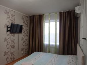 een slaapkamer met een bed en een televisie aan de muur bij Квартира in Aqtöbe