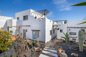 een huis met witte muren en trappen en cactussen bij El Jable Rentals in Arrieta