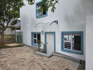 a white building with blue windows and a door at Ocean Whisper in Plettenberg Bay