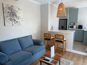 a living room with a blue couch and a kitchen at Ocean Whisper in Plettenberg Bay