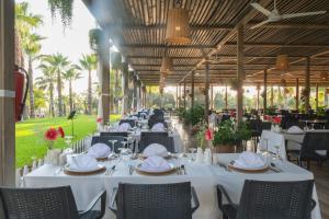 a restaurant with white tables and chairs and palm trees at Sural Resort Hotel in Side