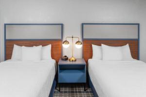 a hotel room with two beds and a table with a lamp at AmericInn by Wyndham Plymouth in Plymouth +26 photos