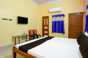 a bedroom with a bed and a desk and a television at Super Hotel O A.R. Lodge in Durgāpur