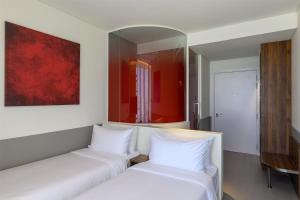 2 letti bianchi in una stanza con specchio di Wink Danang Centre, Unscripted by Hyatt a Da Nang