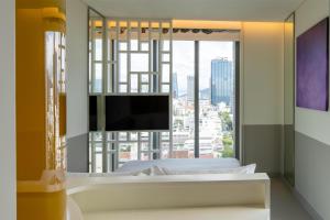 una camera da letto con una grande finestra e una TV di Wink Danang Centre, Unscripted by Hyatt a Da Nang
