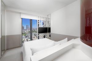 a white bedroom with a view of a city at Wink Danang Riverside, Unscripted by Hyatt in Da Nang