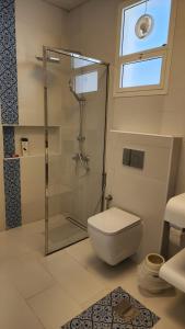 a bathroom with a toilet and a glass shower at Sun & moon in Būbādī +12 photos
