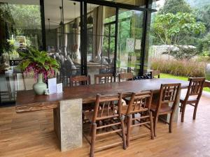 a large wooden table with wooden chairs and a large window at Villa De View in Ban Tham