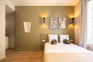 een slaapkamer met een bed en twee schilderijen aan de muur bij Stylish & Cozy Air-Conditioned Studio in Pré Saint Gervais +5 foto's