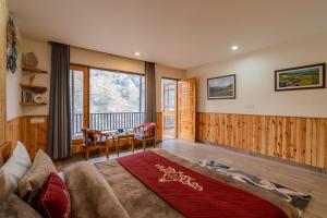 a bedroom with a bed and a desk and a table at SaffronStays Tirthan House - Balcony View in Bandal