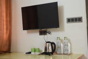 een flatscreen-tv aan de muur met een waterkoker bij Aakruthi Homestay in Davangere