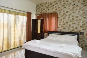 a bedroom with a bed with white sheets and a window at Aakruthi Homestay in Dāvangere