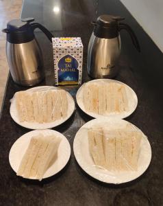 a counter with four white plates with sandwiches on them at Royal Raven Hotel & Banquet' Greater Noida Nearby India Expo Centre & Mart in Greater Noida
