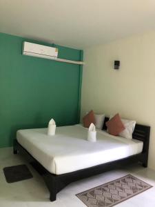 a bed in a room with a green wall at Lanta Vacation House in Ko Lanta