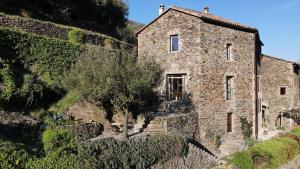 an old stone building next to a stone wall at La Clède du PontNeuf in Valleraugue