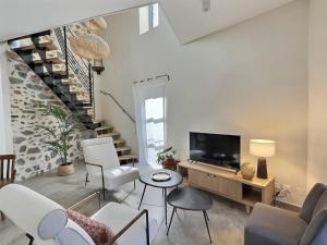 a living room with white furniture and a tv at La Clède du PontNeuf in Valleraugue