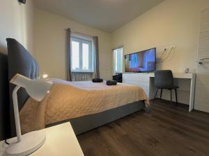 a bedroom with a bed and a desk and a television at Suite Rossini - 100mq con parcheggio gratuito in Alessandria